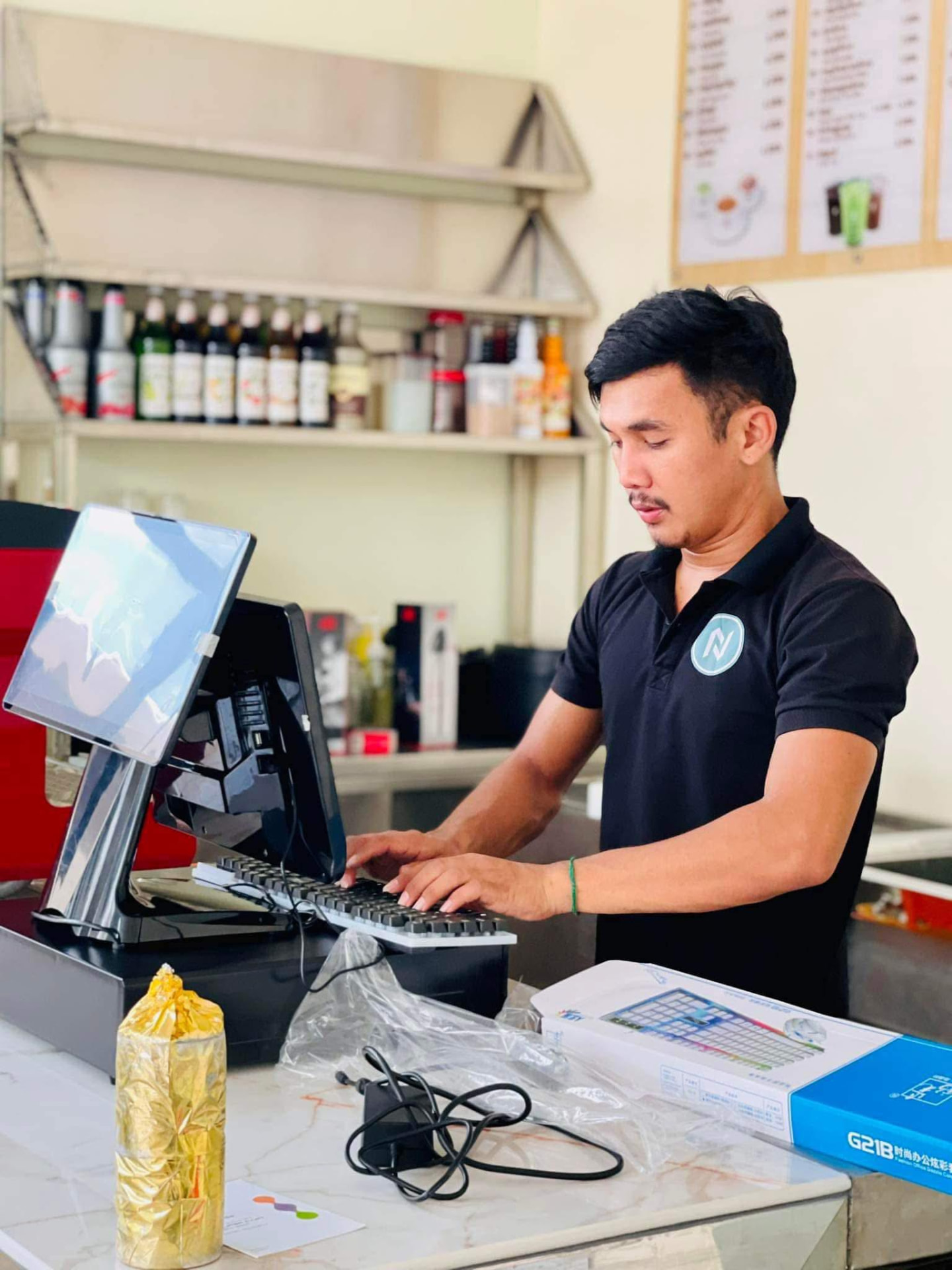 Technician configuring a POS terminal at a café counter
